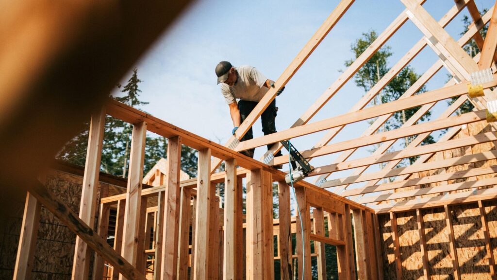 Estrutura de telhado em madeira com tesouras, terças e caibros durante a construção.